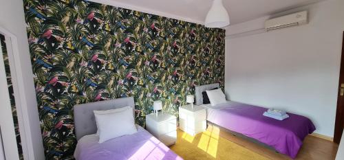 a room with two beds and a wall mural at NuvemCristina in Olho Marinho