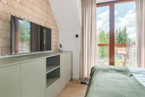a bedroom with a flat screen tv on a wall at Tatra Resort & SPA in Kościelisko