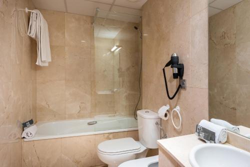 a bathroom with a tub and a toilet and a sink at Madrid Airport Suites, Affiliated by Meliá in Madrid