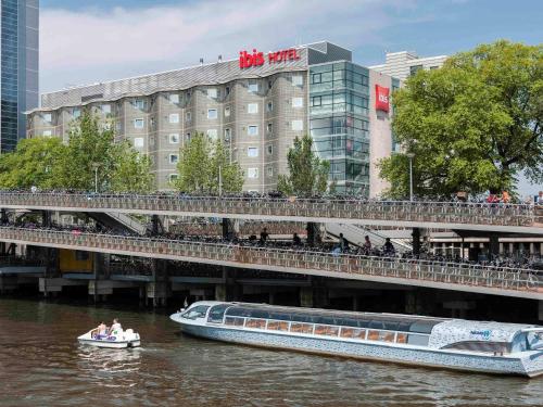 un barco en el agua cerca de un puente con un edificio en ibis Amsterdam Centre, en Ámsterdam
