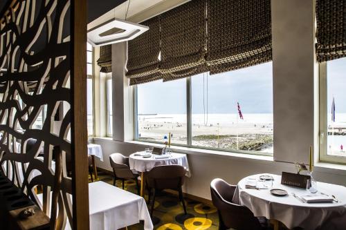 a restaurant with tables and a view of the beach at Hotel Atlantic in Wimereux