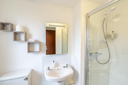 a white bathroom with a sink and a shower at Bracken Lodge 6 with Hot Tub in Belladrum