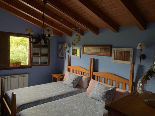 1 dormitorio con 2 camas y paredes azules en La Milonga en Piloña