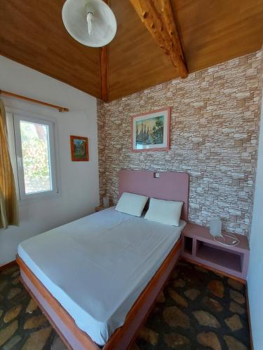 a bedroom with a bed and a brick wall at Beautiful house located on a hill with a spectacular sea view in Samos Island in Koumeika