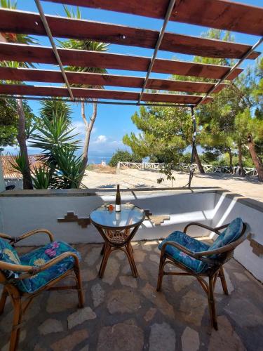 a patio with two chairs and a table with a bottle on it at Beautiful house 800m from Koumeika, Samos in Koumeika