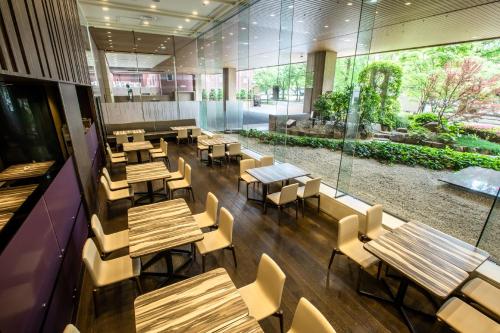 an empty restaurant with wooden tables and chairs at ANA Crowne Plaza Hiroshima by IHG in Hiroshima
