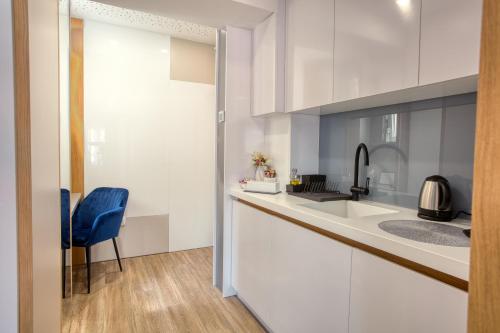 a kitchen with white cabinets and a blue chair at OLD TOWN Apartments by Nejra in Sarajevo