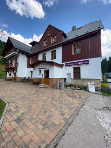 a large red and white building with a courtyard at Pension Bystřenka in Špindlerův Mlýn
