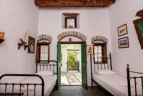 um quarto com duas camas e uma porta aberta em Itonia House em Amorgós