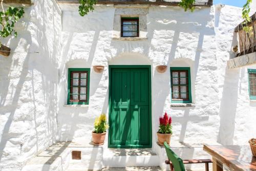 a white building with a green door and windows at Itonia House in Amorgos