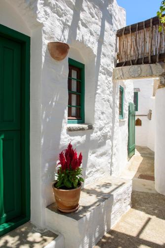 a white building with a green door and a potted plant at Itonia House in Amorgos
