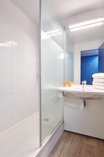 a white bathroom with a shower and a sink at ibis budget Bayonne in Bayonne