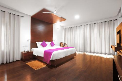 a bedroom with a large bed with purple pillows at Malabar Ocean Front Resort And Spa, Bekal in Nīleshwar
