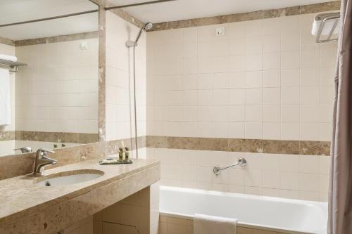 uma casa de banho com uma banheira e um lavatório e uma banheira em B&B HOTEL Sado Setúbal em Setúbal