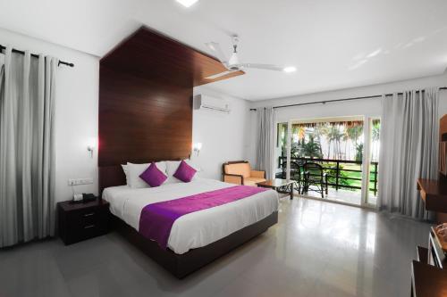 a bedroom with a large bed and a balcony at Malabar Ocean Front Resort And Spa, Bekal in Nīleshwar