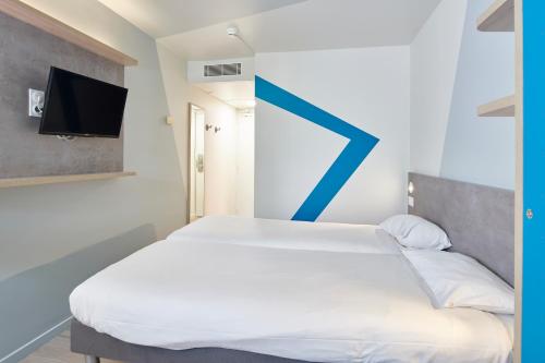 a bedroom with a bed with a blue arrow on the wall at ibis budget Bayonne in Bayonne