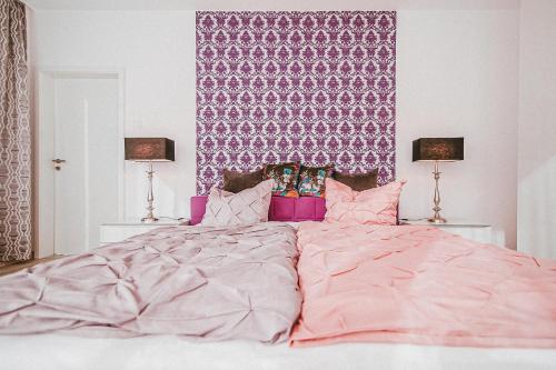 a large bed with a pink comforter and two lamps at Villa Baldursheim in Zinnowitz