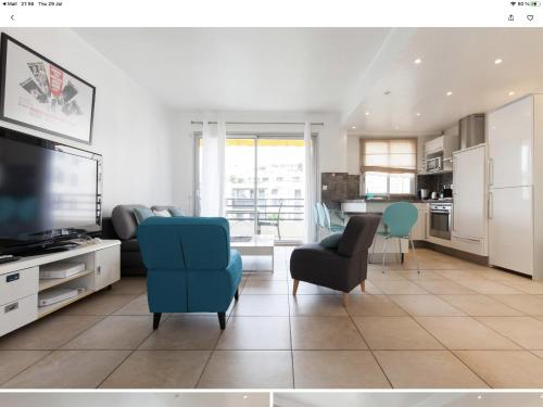 a living room with a blue chair and a tv at Palais Rouaze in Cannes