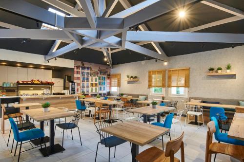 a restaurant with wooden tables and blue chairs at ibis budget Bayonne in Bayonne