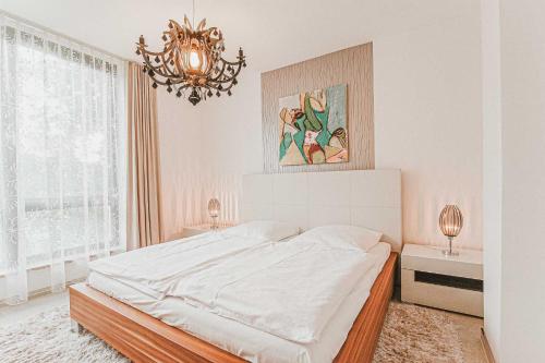 a white bedroom with a large bed and a chandelier at Villa Baldursheim in Zinnowitz