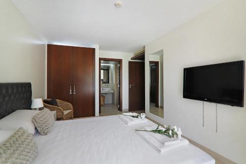 a bedroom with a large bed with a flat screen tv at Salgados 4seasons Apartment in Albufeira