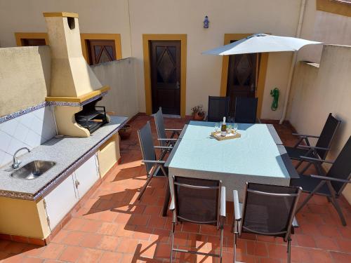 a kitchen with a table and chairs and an umbrella at Casa do Facho in São Martinho do Porto
