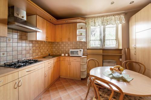 una cucina con armadi in legno, tavolo e forno a microonde di Apartament przy Parku a Kudowa-Zdrój