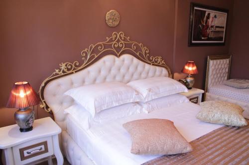 a bedroom with a white bed with two tables and two lamps at Hotel Boutique Vila Fernando Tirana in Tirana