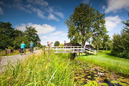 two people riding bikes on a bridge over a river at Weerribben Wieden gastenverblijf in Wanneperveen