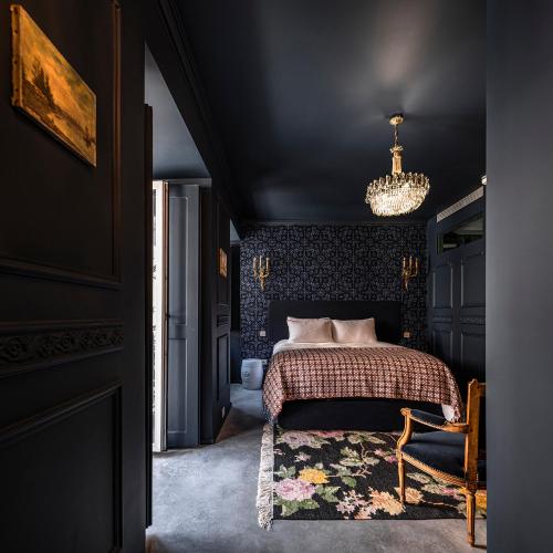 a black bedroom with a bed and a chandelier at toctoctoc lisboa in Lisbon