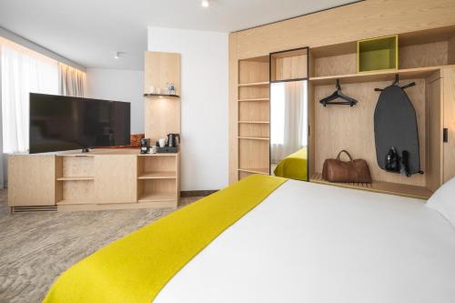 a bedroom with a bed and a tv and a yellow blanket at Mercure Katowice Centrum in Katowice