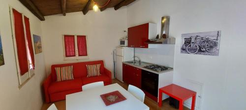una pequeña cocina con sofá rojo y mesa en Casa Turano, en Castellammare del Golfo