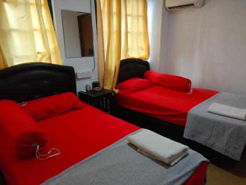 two beds in a room with red pillows on them at ASH HOTEL in Seremban