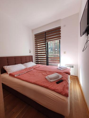 a bedroom with a bed with a red comforter and a window at Apartman Green Lux - Balkan Hil 1 in Zlatibor