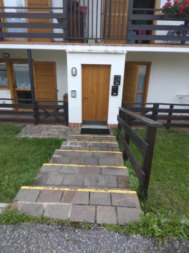 a house with a wooden door and a stone walkway at La casa di Grace nella valle incantantata in Carano