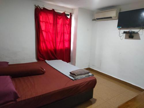 a room with a red curtain and a bed in front of a window at ASH HOTEL in Seremban