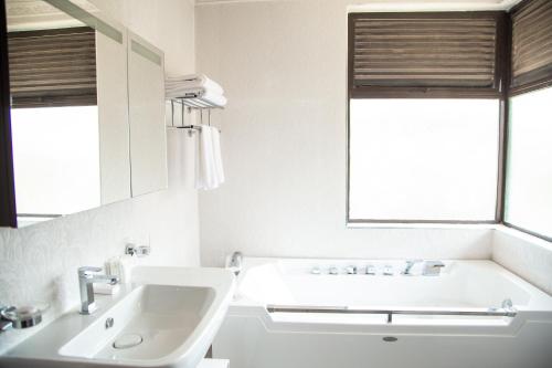 Baño blanco con lavabo y espejo en Elmer Resort & Spa Naivasha en Naivasha