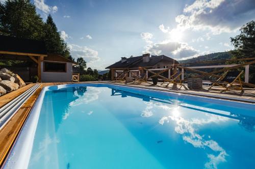 a large blue swimming pool with a house in the background at Gościniec Rajec in Rajcza