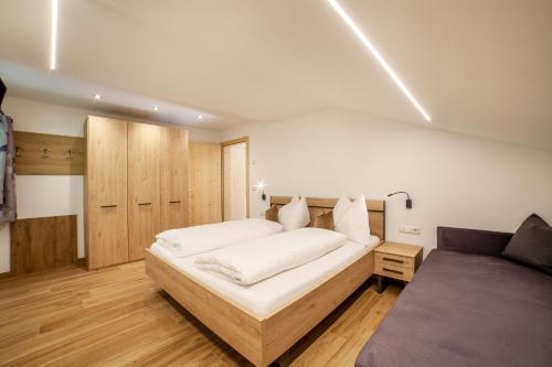 a bedroom with a large white bed and a couch at Innergasserhof Ferienwohnung Edelweiss in San Martino