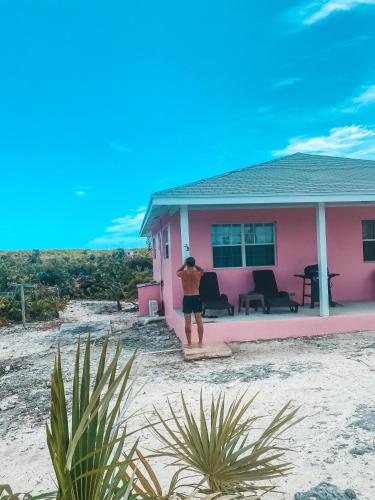 a man standing in front of a pink house at Tropical View Villas in Hartswell