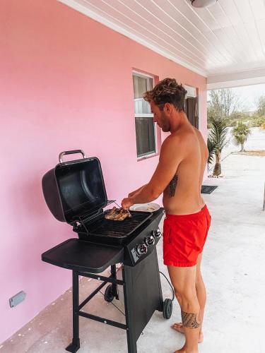 a man in red shorts cooking food on a grill at Tropical View Villas in Hartswell