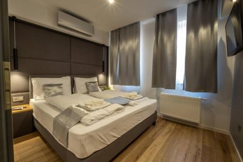 a bedroom with a large bed with white sheets at Minaret Residence & Relax Pécs in Pécs