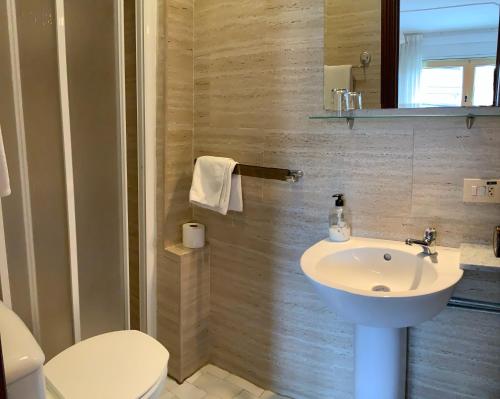 a bathroom with a white sink and a toilet at Hotel España in Lugo