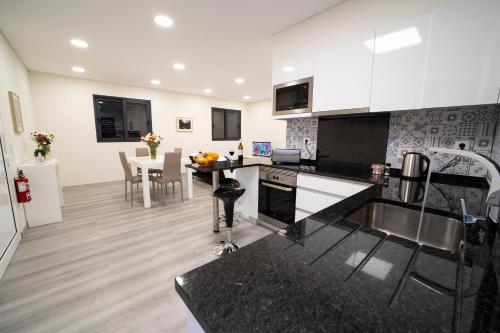 uma cozinha com balcões a preto e branco e uma mesa em Coração da Madeira em Curral das Freiras