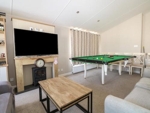 a living room with a pool table and a flat screen tv at The Goodwood Lodge in Chichester