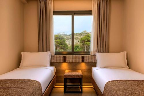 two beds in a room with a window at Radisson Blu Residences Al Hoceima in Al Hoceïma