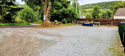 a gravel driveway with a tree and a fence at Self catering upper floor flat at Woodend house in Balmacara