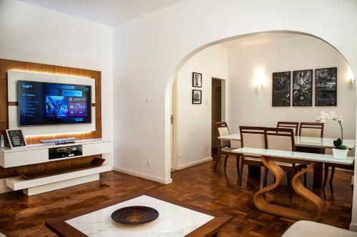 ein Wohnzimmer mit einem TV und einem Esszimmer in der Unterkunft Amazing in Ipanema by Verlaine Adami in Rio de Janeiro