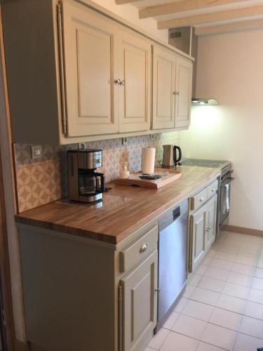 une cuisine avec des armoires blanches et un comptoir en bois dans l'établissement Ambiance Seine - appartement 46m2 terrasse - Hortensia, à Thomery