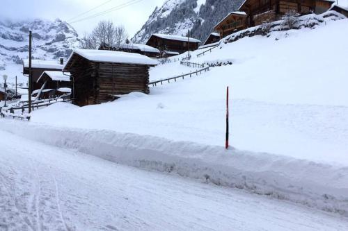 a snow covered road in front of a cabin at Olle and Maria's B&B- apartment in Gimmelwald